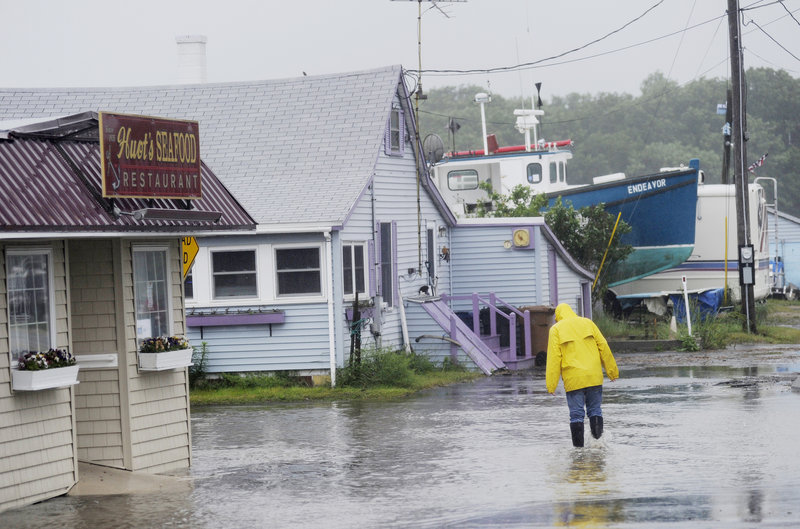 Michael Clair of Biddeford walks down a flooded Bay Avenue in front of Huot’s Restaurant at Camp Ellis in Saco on Monday. Saco got just over 6 inches of rain in three days.