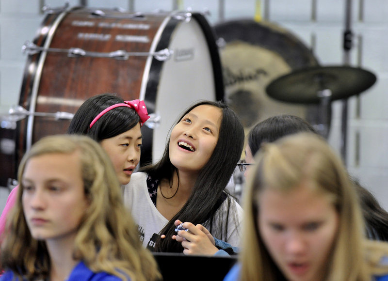 Hu Yanjie looks up while laughing at photos taken by one some of her classmates from China while sitting in on a band class Monday at Falmouth Middle School. Falmouth students acted as tour guides and classroom buddies for their guests.