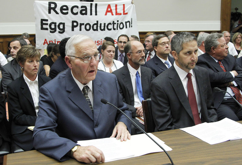 Protesters unfurl a banner as Iowa egg farm owner Austin “Jack” DeCoster, left, testifies in 2010 at a House subcommittee hearing on an outbreak of salmonella in eggs. DeCoster previously owned an egg farm in Maine that had a reputation as a harsh workplace.