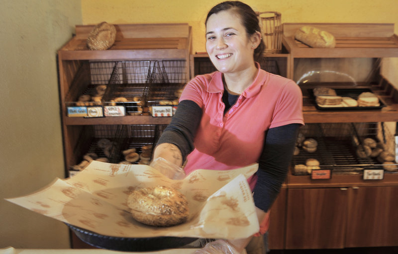 Store manager Amy Christiansen offers a customer a toasted bagel sandwich at The Works Bakery Cafe on Temple Street in Portland.