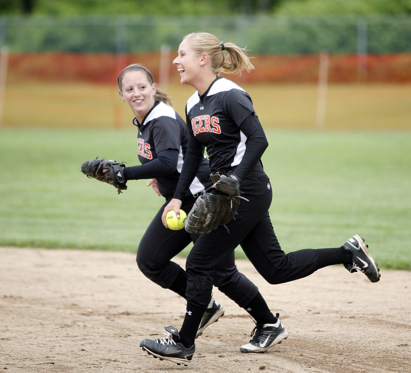 Kristina McCurry, left, and Mariah Albert of Biddeford share a laugh Tuesday after Albert made a tough catch in right field to end an inning. The defense helped the Tigers preserve a 2-0 victory and advance to the quarterfinals of the Western Class A softball tournament.