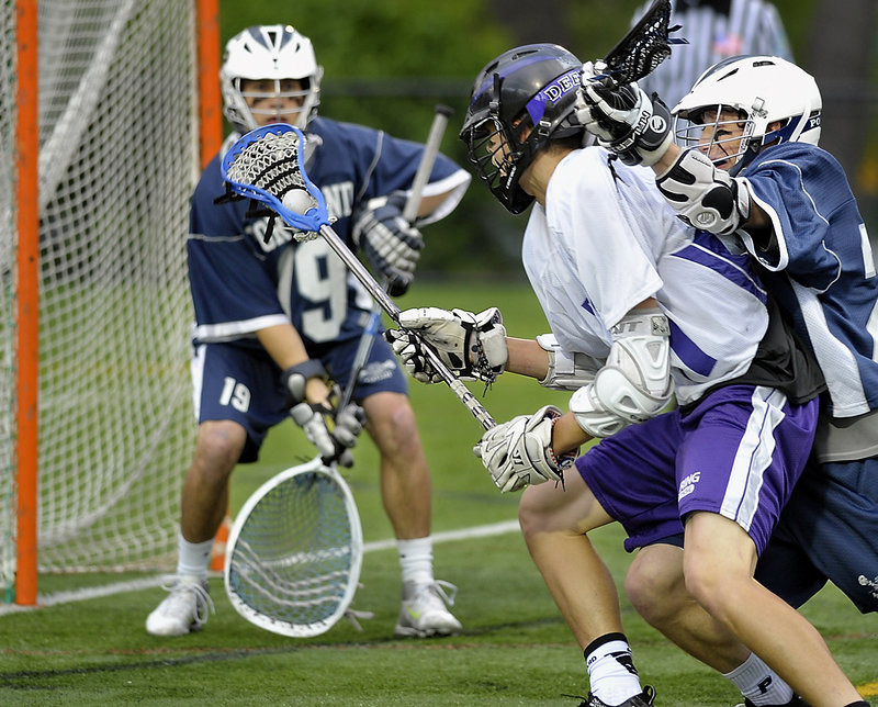 Anthony Verville of Deering breaks deep into the Portland zone Tuesday night while attempting to get a shot off against goalie Ryan Jurgelevich. Andrew Schwartz of Portland, right, plays tough defense. Deering scored in overtime for a 7-6 victory.