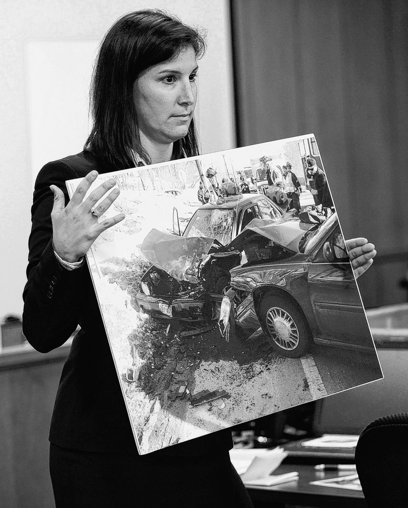 The prosecutor shows jurors a photograph from the auto crash during the trial of Aaron Deveau, above, in Haverhill District Court Tuesday.