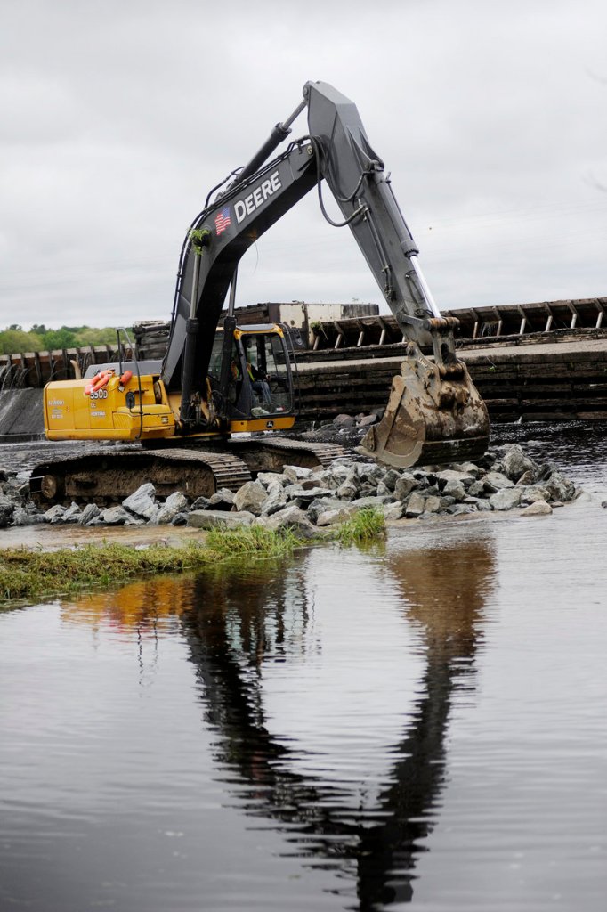 Workers move rocks last week as they build an access road to the Great Works Dam on the Penobscot River. The dam’s demolition, starting Monday, is part of a river restoration project that will include removal of the Veazie Dam.