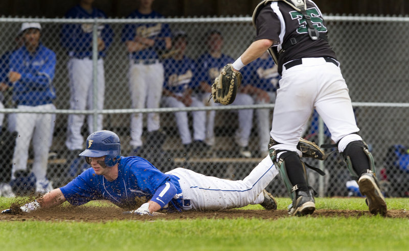 Grayson Beressi of Falmouth dives into the plate to score Thursday during a five-run third inning that helped the Yachtsmen earn a 7-3 victory against Spruce Mountain in their Western Class B quarterfinal. The Spruce Mountain catcher is Brandon Hodges.
