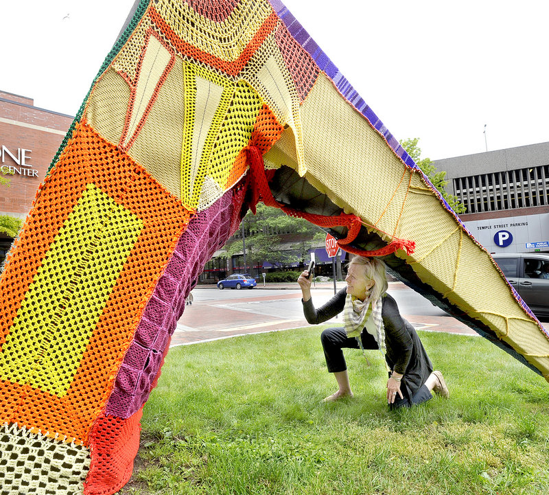 Jean Barash of Wilson, Wyo., takes a photo of a sculpture outside One City Center in Portland on Friday. It was covered in yarn as a prelude to International Yarn Bombing Day today.