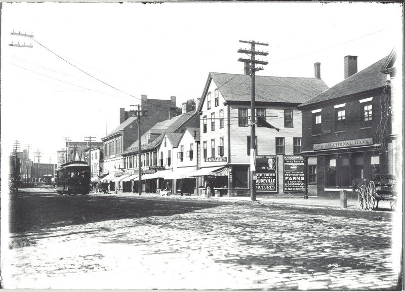 An electric trolley, above, rolls its way down Main Street in Saco circa 1920. Saco National Bank can be seen on the right at Main and Storer streets. Farther up the street is a garage covered with advertisements, as well as Edwin W. Fay’s grocery store. Below, as seen in a photograph taken Thursday, the same stretch of road as it appears today.
