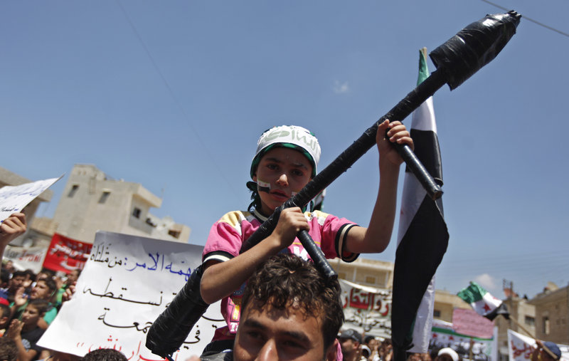 A Syrian boy carries a toy rocket launcher during an anti-Bashar Assad protest on the outskirts of Idlib, Syria, Friday.