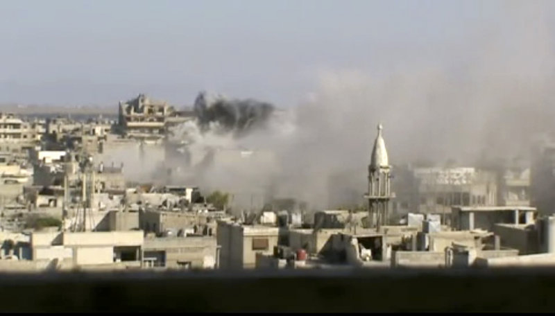 Image made from amateur video released by Shaam News Network and accessed Friday purports to show explosions in the Khaldiyeh area of the central city of Homs, Syria.