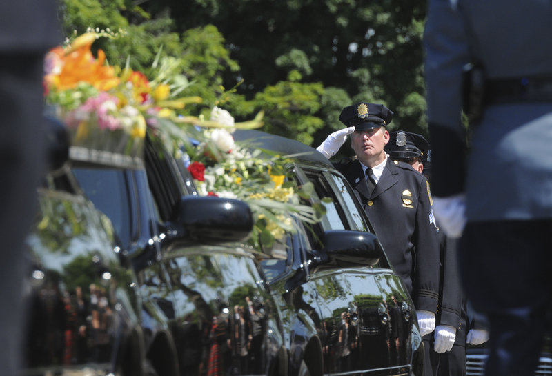Springfield, Mass., police Sgt. Neil Maloney salutes the hearse bearing the casket of fallen Springfield police Officer Kevin Ambrose on Friday in Springfield.