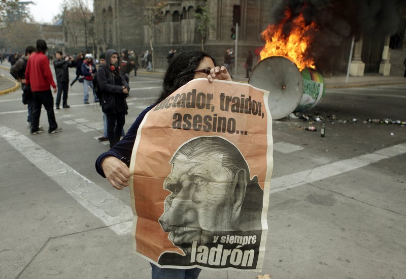 A woman holds a poster depicting Gen. Augusto Pinochet, who governed Chile from 1973 to 1990, during a protest Sunday in Santiago, Chile, at the premiere of a pro-Pinochet documentary. The writing reads in Spanish: “Dictator, traitor, killer ... and always thief.”