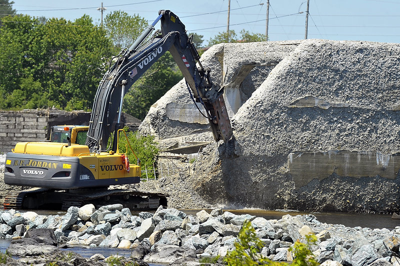 An operator of heavy equipment begins to break up the concrete fishway to start the $62 million Penobscot River project Monday.