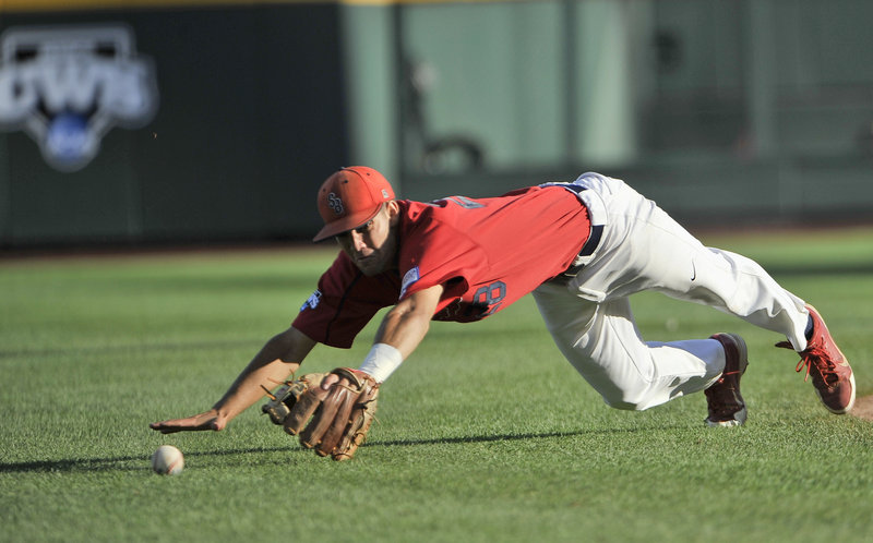 Stony Brook shortstop Cole Peragine can’t reach a single by UCLA’s Pat Valaika during their College World Series opener Friday in Omaha, Neb. UCLA won, 9-1.