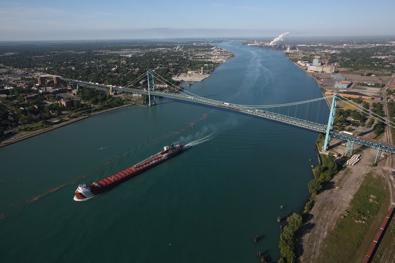 In this aerial photo, a freighter passes by the Ambassador Bridge that links Detroit on the right and Windsor, Ontario, on the left on Thursday.