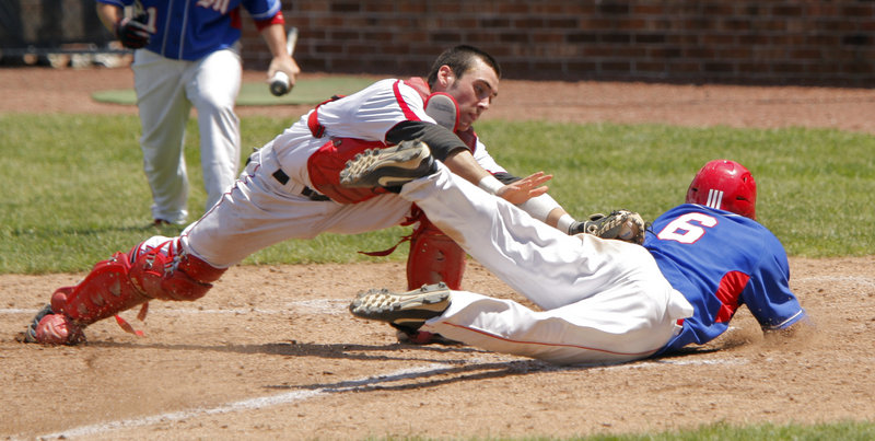 Travis St. Pierre of Messalonskee dives across the plate as Scarborough catcher Conor McCann applies the tag during the Class A baseball final. St. Pierre was called out, but Messalonskee earned its first Class A title with a 6-3 win.