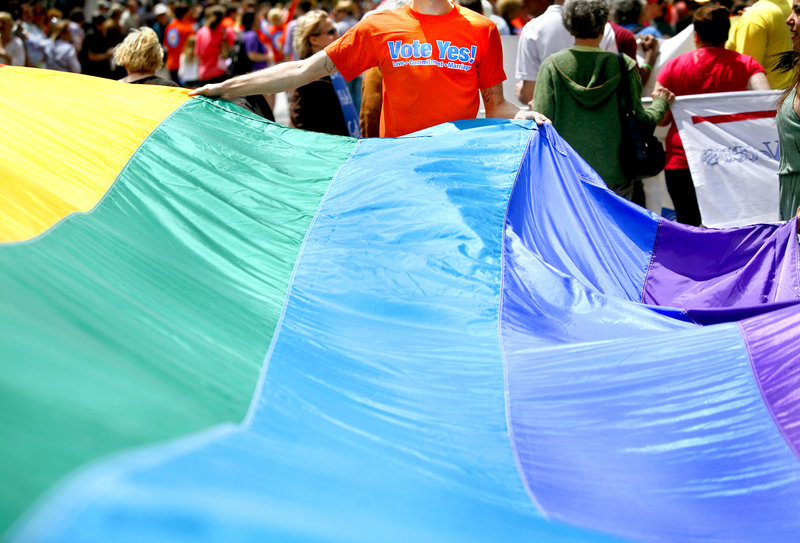 Chris Sawyer of South Portland, with Mainers United for Marriage, helps carry a rainbow flag during the Southern Maine Pride Parade and Festival on Congress Street in Portland on Saturday.