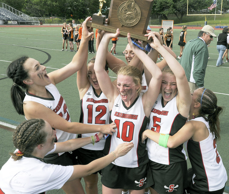 Breanna Good, left, Laura Przybylowicz (12), Maggie Smith (10) and Kelsey Howard (5) help raise the championship plaque after Scarborough held off Brunswick 11-9 to win its third consecutive Class A girls' lacrosse title.