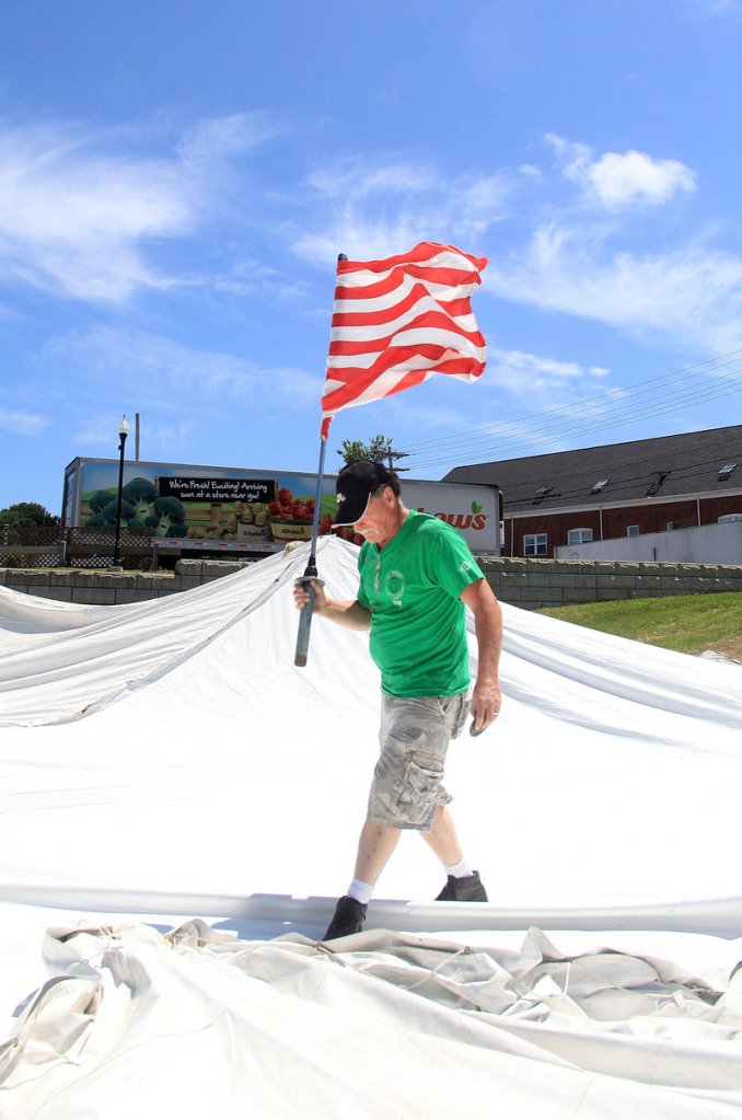 Joseph LeBlond, production manager for La Kermesse, carries an American flag on Sunday that will fly atop the main entertainment tent during the festival, which runs Thursday through Sunday in downtown Biddeford.