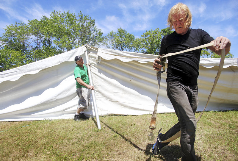 Tom Brady, front, and Joseph LeBlond work together to set up the main entertainment tent on Sunday for the 30th anniversary of La Kermesse festival in Biddeford.