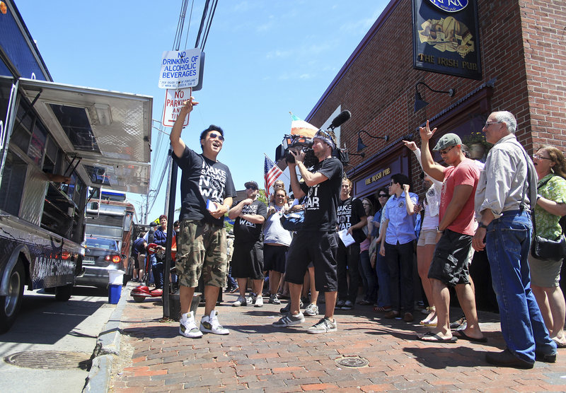 Ted Kim, center, leads the gathering crowd in a cheer just before opening the Seoul Sausage truck as “The Great Food Truck Race” is filmed for the Food Network in Portland outside of Ri Ra’s Irish Pub on Commercial Street on Sunday.