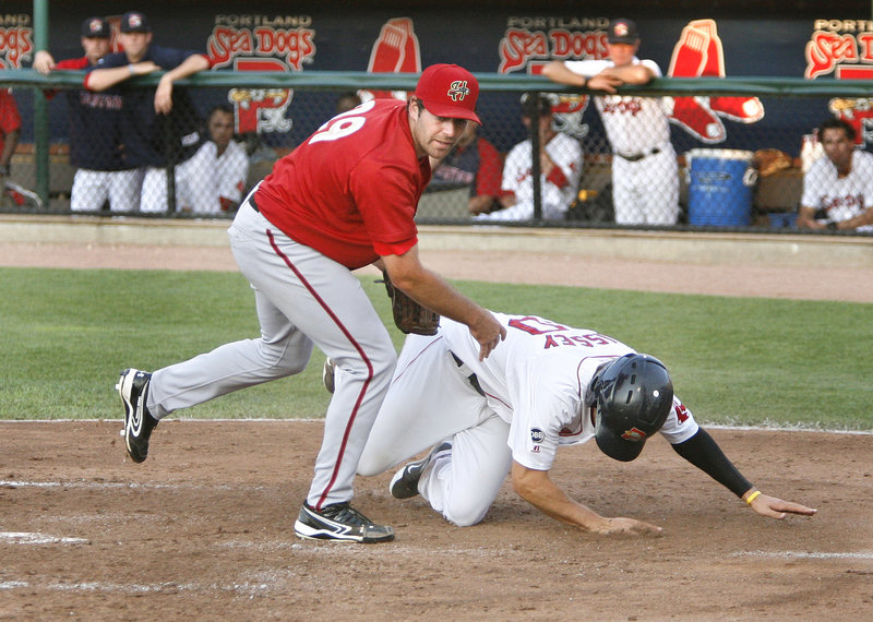 Peter Hissey of the Sea Dogs tumbles next to Harrisburg pitcher Robert Gilliam after scoring on a passed ball Thursday night. Hissey was a home run shy of a cycle, leading the Sea Dogs to a 6-1 victory.