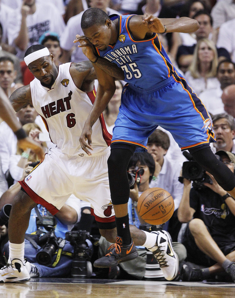 LeBron James, left, of the Miami Heat and Kevin Durant of the Oklahoma City Thunder compete for a loose ball Thursday night. Miami won the NBA title with a 121-106 victory.