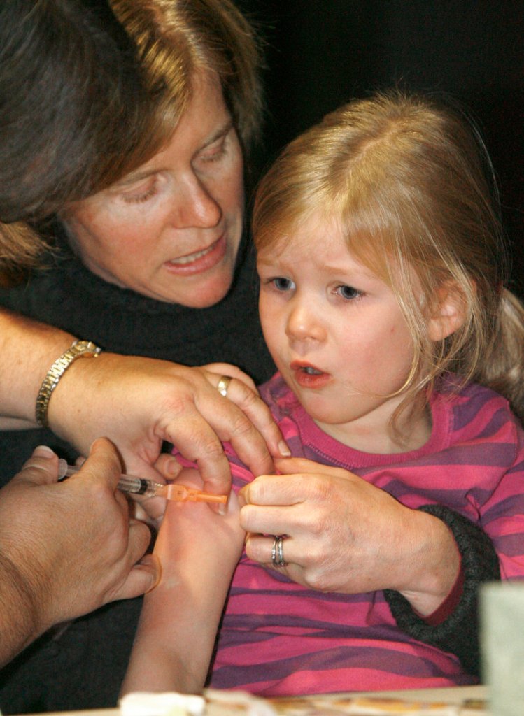 A mother holds her daughter as she awaits a flu shot in Duxbury, Vt., in 2009. In Maine, more than 226,000 people received immunizations and other preventive care services over the last year with no out-of-pocket costs, thanks to the Affordable Care Act, two legislators say.