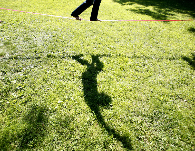Evan Lewis of Portland practices his slacklining skills Thursday as he balances on a nylon webbing tied to two trees at Deering Oaks park in Portland.