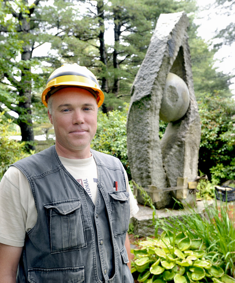 Sculptor Jesse Salisbury stands in front of “Tidal Moon,” his 14-foot granite artwork, as it was being readied for transport last Saturday from the Yarmouth residence of William and Mary Louise Hamill.