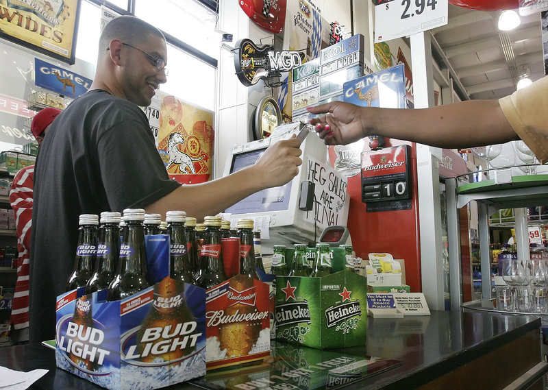 A clerk checks the ID of a customer buying beer at a store in Nashville, Tenn., in 2006. Parents need to be role models of lawful behavior by refusing to host gatherings where underage drinking is going on, a reader says.