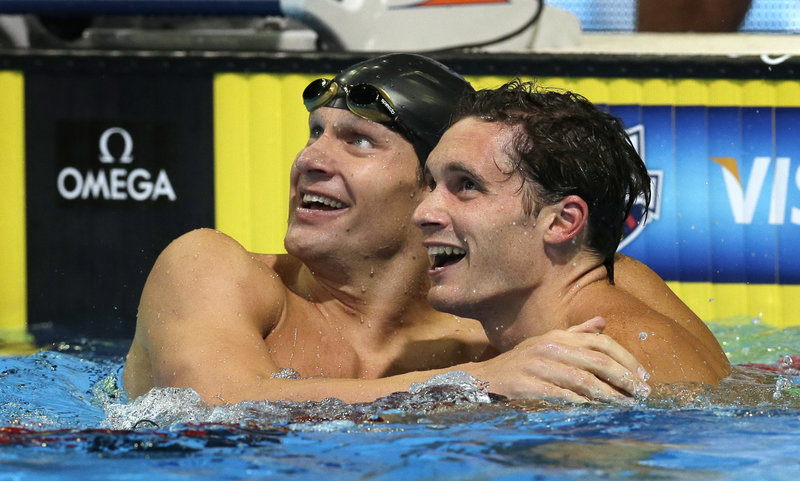 Brendan Hansen, left, is congratulated by second-pace finishers Eric Shanteau after winning the men’s 100-meter breaststroke final Tuesday, rallying on the final lap to finish with a time of 59.68 seconds.