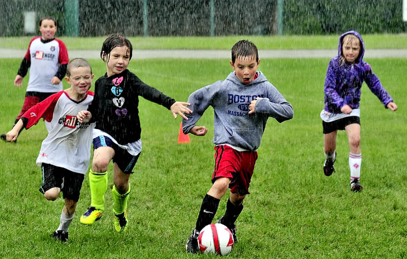 The pouring rain did not stop these kids including Luke Carey as he breaks free with ball during practice in the Challenger Sports soccer program at Carrabec High School on Tuesday.