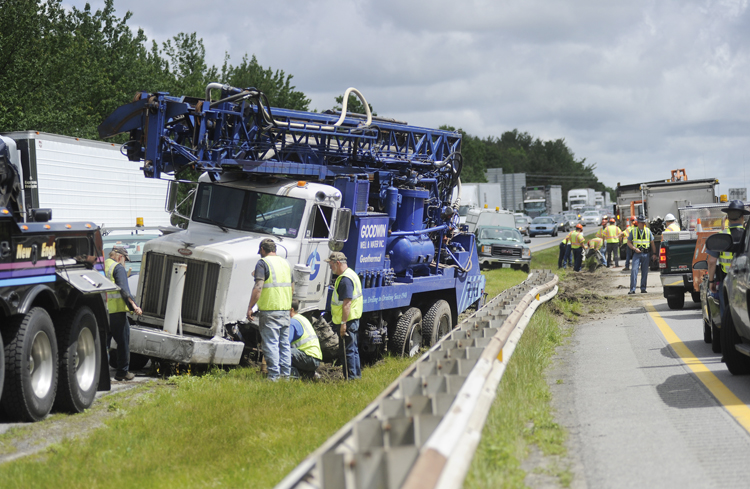 Crews work to clean up debris and prepare to tow a truck that crashed into the guard rail at mile 50 while traveling south on the Maine Turnpike in Falmouth today. There were no injuries in the crash but traffic was backed up for about two miles in the northbound lane where debris from the guard rail landed in the road.