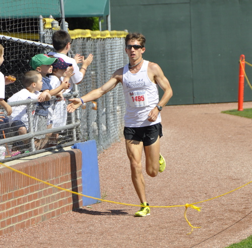 Jonny Wilson of Freeport is greeted by spectators as he approaches the finish line to win the Portland Sea Dogs Father's Day 5K at Hadlock Field.