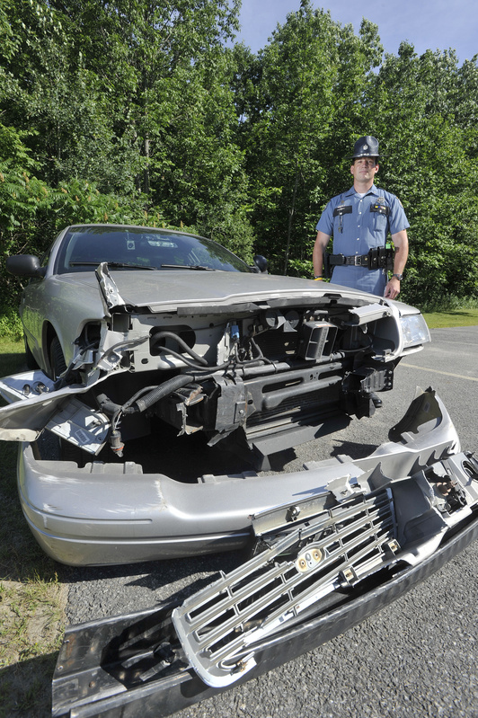 Maine State Police Trooper Douglas Cropper is shown Saturday beside his police cruiser, which was damaged while stopping a wrong-way driver on I-295 on Friday.