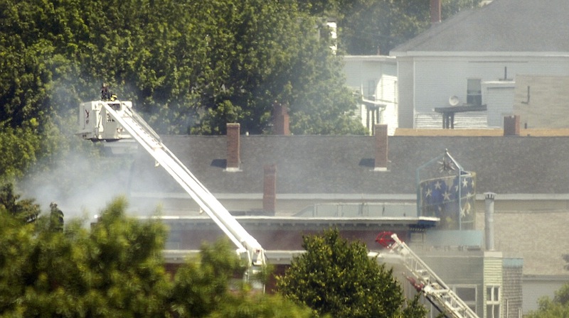 A Portland firefighter lowers a basket closer to the roof of a fire on Montgomery Street in Portland on Monday, July 2, 2012.