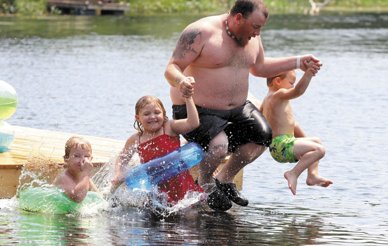 Jason Madore of Vassalboro jumps off a floating swim dock with three of his kids while cooling off in the middle of Outlet Stream in North Vassalboro on Sunday. From left to right are Jayden Madore, 5, Miah Deckard, 5, and Kendrick Williamson, 4.