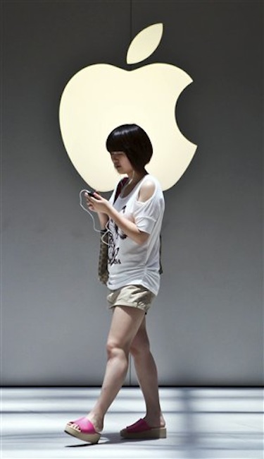 A woman walks near the Apple logo outside an Apple store in Shanghai, China on Monday July 2, 2012. Apple agreed to pay $60 million to settle a dispute in China over ownership of the iPad name, a court announced Monday, removing a potential obstacle to sales of the popular tablet computer in the key Chinese market. (AP Photo)