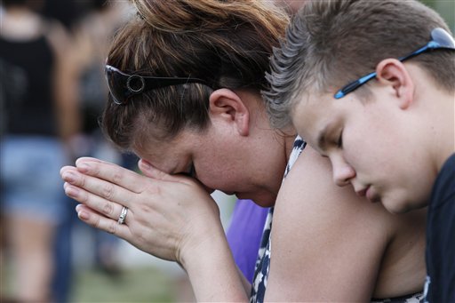Dylan Bowen, 13, right, holds onto his mother Lorri Hastings as they pray on Sunday, in Aurora, Colo., during a prayer vigil for the victims of Friday's mass shooting at a movie theater.