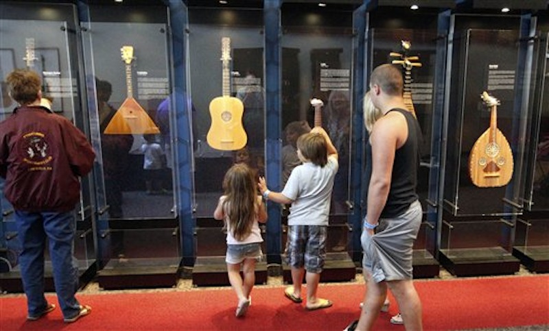 In this Tuesday, June 26, 2012 photo, visitors walk by the display of the instruments that is part of the touring National Guitar Museum exhibit on display at the Carnegie Science Center in Pittsburgh, through Sept. 30, 2012. The National Guitar Museum is a traveling guitar museum searching for a home. Museum director HP Newquist said the initial plan was to take it on the road for five years, to find out which city was the most hospitable. The museum is on a nine-city tour. (AP Photo/Keith Srakocic)