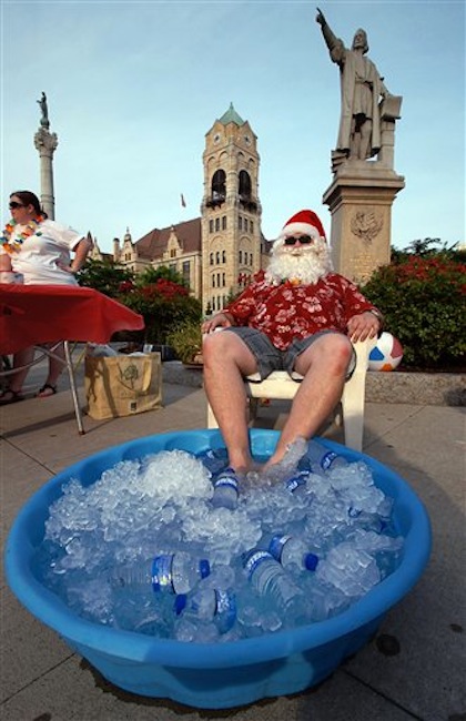 Summer Santa Claus Tom Osborn of Taylor, Pa. a member of the Greater Scranton Jaycees, cools his feet in a pool of ice at Lackawanna County Courthouse Square during First Night festivities held in downtown Scranton, Pennsylvania on Friday, July 6, 2012. (AP Photo/The Scranton Times-Tribune, Butch Comegys)