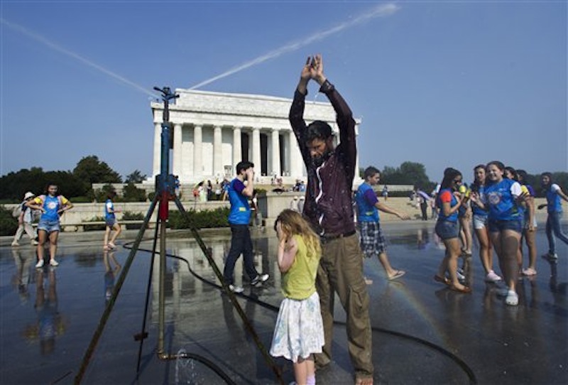 Visitors get much needed relief from a water sprinkler set up at the National Mall near the Lincoln Memorial, rear, in Washington Saturday, July 7, 2012. The heat gripping much of the country is set to peak Saturday in many places, including some Northeast cities, where temperatures close to or surpassing 100 degrees are expected. (AP Photo/Manuel Balce Ceneta)