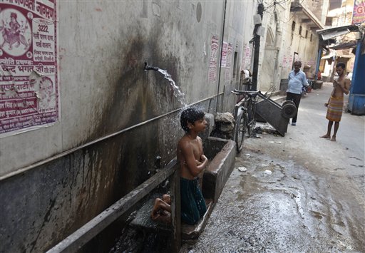 A boy sits under a running tap at a street to cool off on a hot afternoon in New Delhi, India, last Sunday. Northern India has been experiencing severe hot weather, with maximum temperatures touching around 113 degrees in some areas.