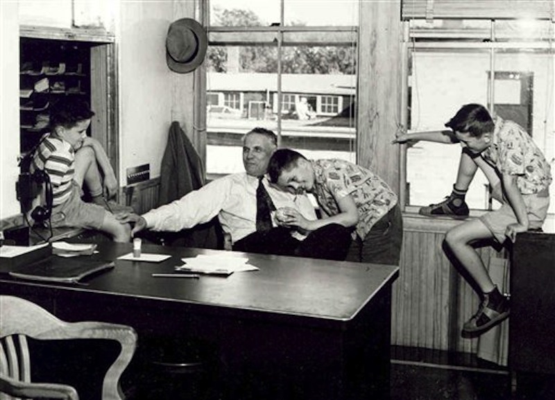 In this 1941 file photo provided by the L.L. Bean Archive, Leon Leonwood Bean spends time with grandsons, from left, Leon Gorman, Jim Gorman, and Tom Gorman, at Bean's office in Freeport, Maine. As outdoors outfitter L.L. Bean celebrates its 100th anniversary, it's still not 100 percent clear what the famous founder's initials stood for. It could be Leon Leonwood Bean, as the company claimed for decades, or was it Leon Linwood Bean, as his grandson suggests. (AP Photo/The L.L. Bean Archive, File)