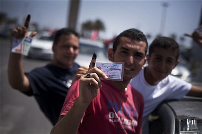 Libyan men hold their elections ID cards while celebrating election day in Tripoli, Libya, Saturday, July 7, 2012. Jubilant Libyan voters marked a major step toward democracy after decades of erratic one-man rule, casting their ballots Saturday in the first parliamentary election after last year's overthrow and killing of longtime leader Moammar Gadhafi. But the joy was tempered by boycott calls, the burning of ballots and other violence in the country's restive east. (AP Photo/Manu Brabo)