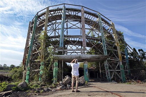 Chuck Damore, who was a regular at Lincoln Park during his youth, takes a photo of some remains of the Comet roller coaster at the defunct amusement park in Dartmouth, Mass., Wednesday July 11, 2012. Demolition crews on Wednesday started tearing down the crumbling roller coaster to clear the site for a development that will include single-family homes, apartments and commercial space. (AP Photo/The Standard-Times, Peter Pereira) entertainment;coaster;roller coaster;wooden;fun;demolition