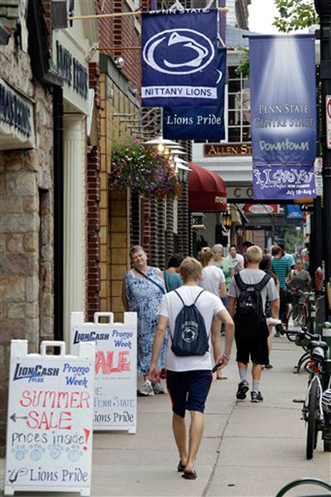 People walk past the shops on College Avenue in the heart of downtown State College, Pa, home of the Pennsylvania State University on Monday, July 23, 2012. State Farm is pulling its ads from broadcasts of Penn State football games, while General Motors is reconsidering its sponsorship deal. (AP Photo/Gene J. Puskar) NCAA