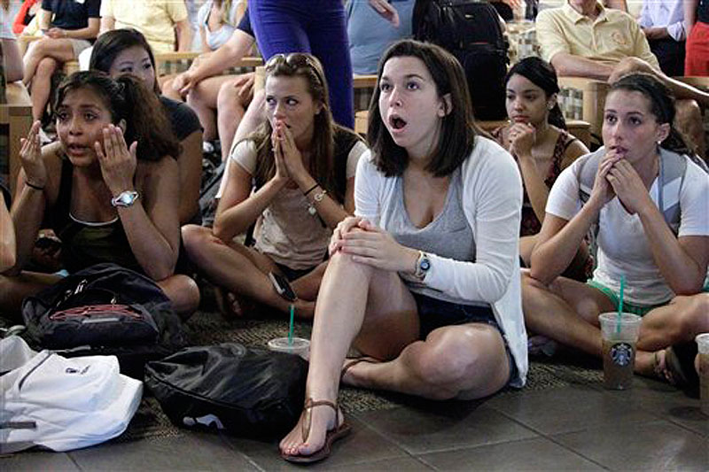 Laura Lovins, a Penn State University sophomore from State College, Pa., center, reacts while listening to a television in the HUB on the Penn State University main campus in State College as the NCAA sanctions against the Penn State University football program were announced Monday.