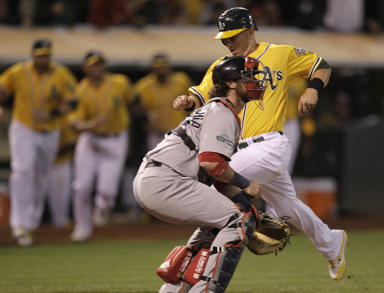 Oakland Athletics' Cliff Pennington, right, scores the game- winning run while Boston Red Sox catcher Jarrod Saltalamacchia waits for the ball in the ninth inning Tuesday in Oakland, Calif. Pennington scored on a sacrifice fly hit by Coco Crisp.