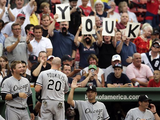 Chicago White Sox third baseman Kevin Youkilis is congratulated by teammates and fans after scoring on a throwing error during the first inning of Monday's game against the Boston Red Sox at Fenway Park.